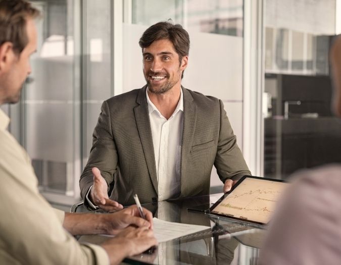 Man in suit consulting two individuals.