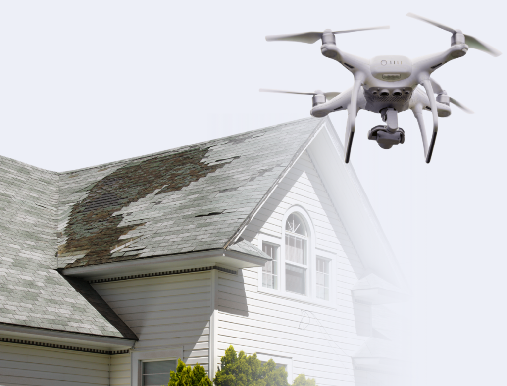 Gray drone hovering over a house with damaged roof shingles