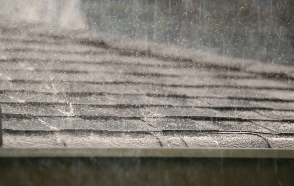 Close up shot of shingled roof showered in rainfall