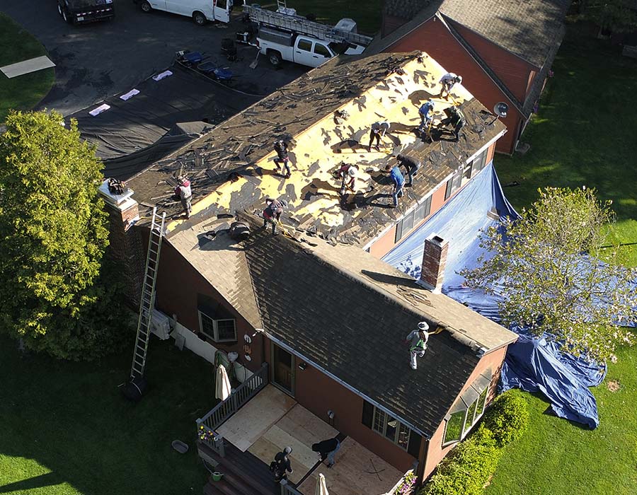 Aerial view of a residence with people on top, replacing the entire roof