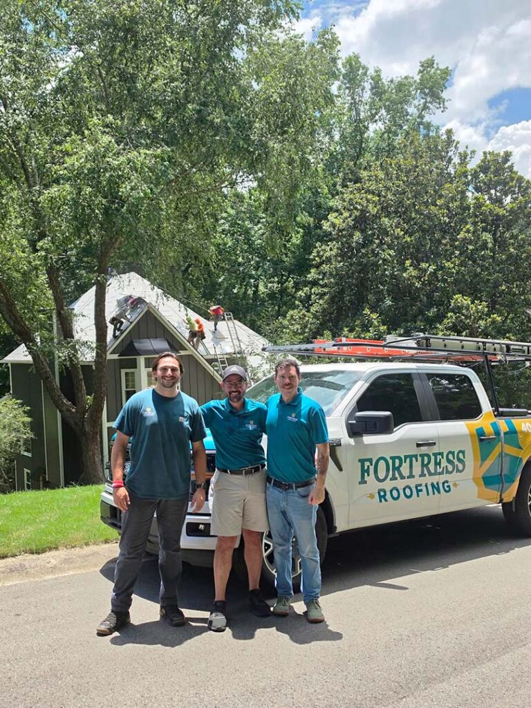 Group photo of three Fortress Roofing workers lined up, with Fortress Roofing vehicle beside them